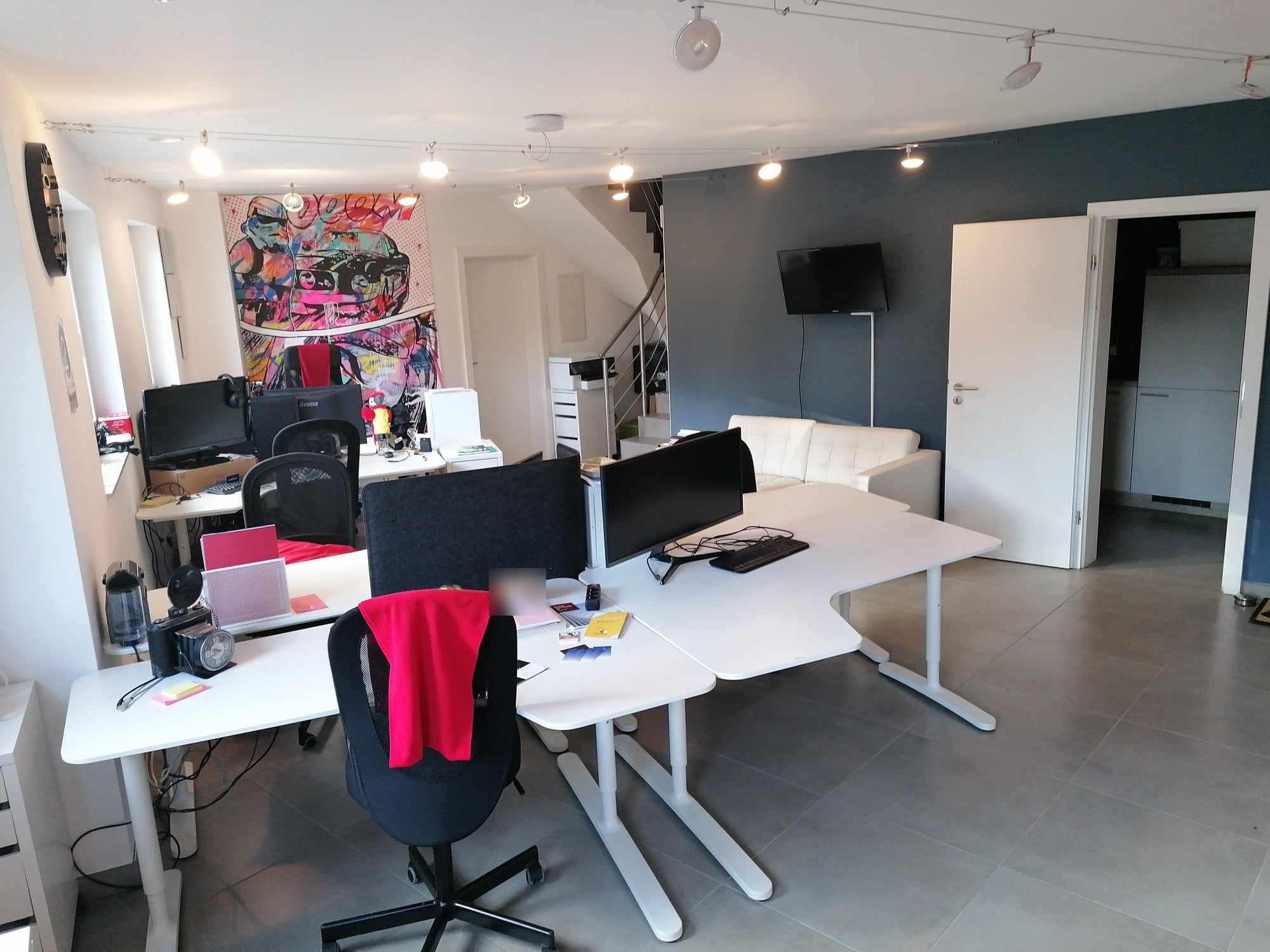 L'open space de 2B Space : bureaux blancs, éclairage sur câbles, canapé et mur bleu ardoise